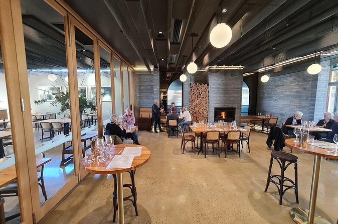 A long tasting room with a wood fire, round tables and glasses set out